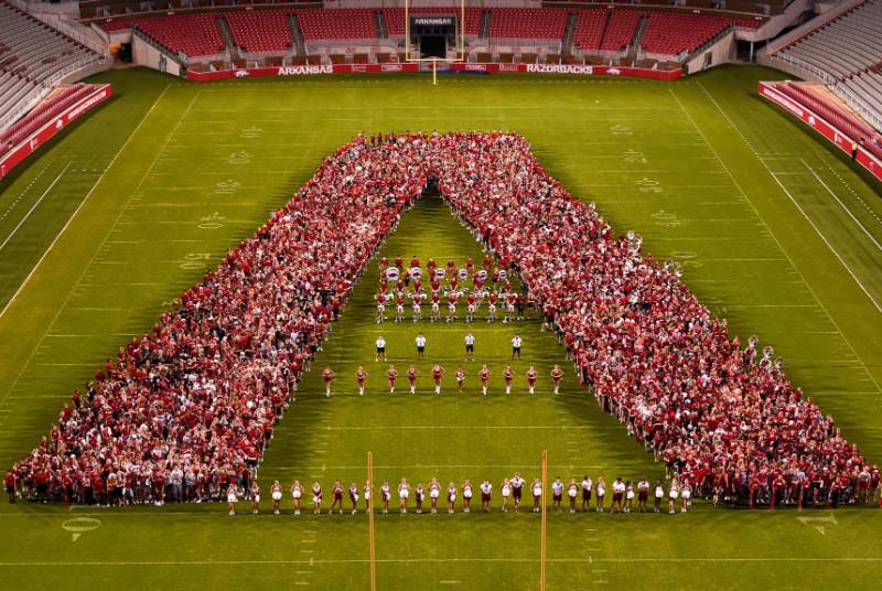 People gathered on a football field forming a large A